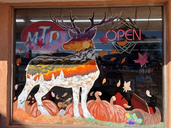 Local artists paint festive artwork on windows of local businesses celebrating fall/hunting season