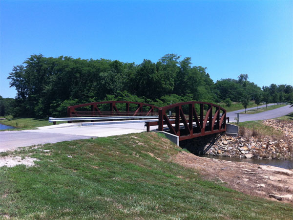 A steel bridge welcomes visitors to the Lansing City Park. 