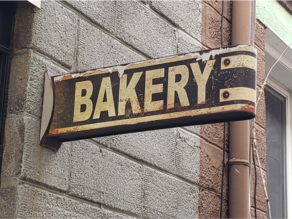 Vintage sign marking the back entrance to M Street Bakery at 117 N Michigan Ave in Howell