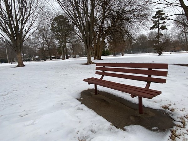 The park bench is empty in the snow
