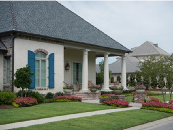 A home with a beautiful front porch and lush landscaping in Grand Pointe