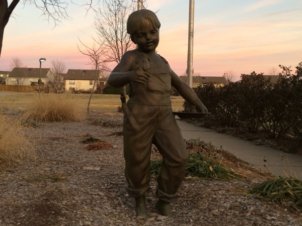 Sculpture of a boy at sunset in front of Sunflower Elementary School