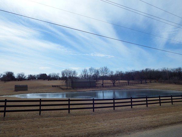 Beautiful blue skies over a fenced-in farm pond in Northwest Lawrence